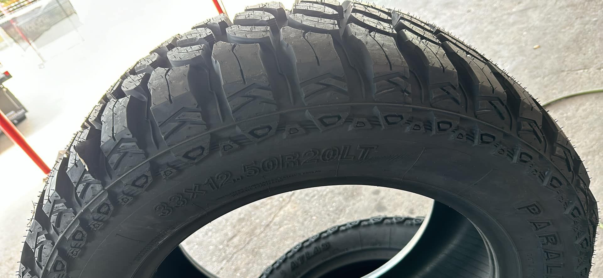 Close-up of a black off-road tire with deep treads, another tire visible below.