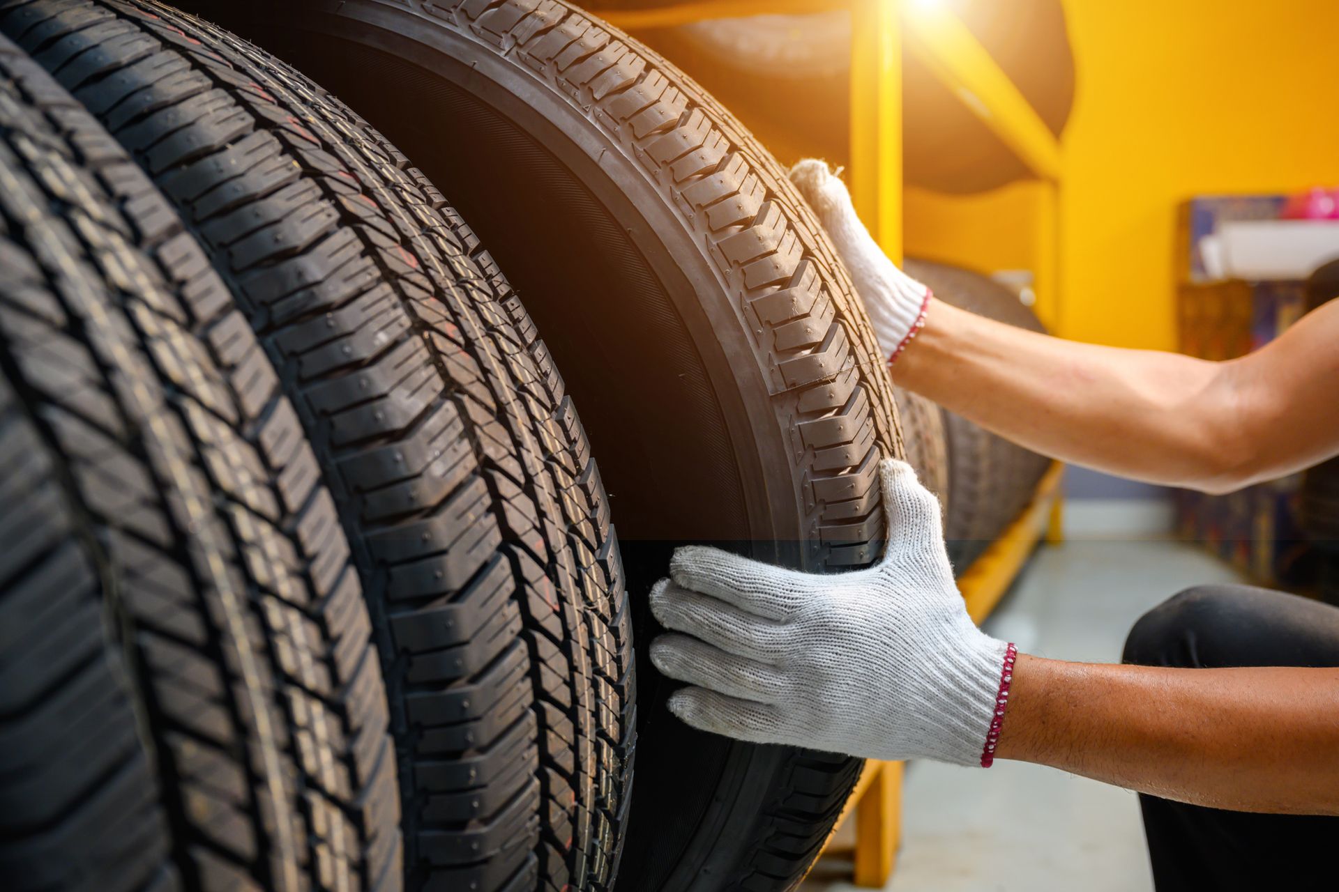 Person in gloves holding a tire in a storage area.