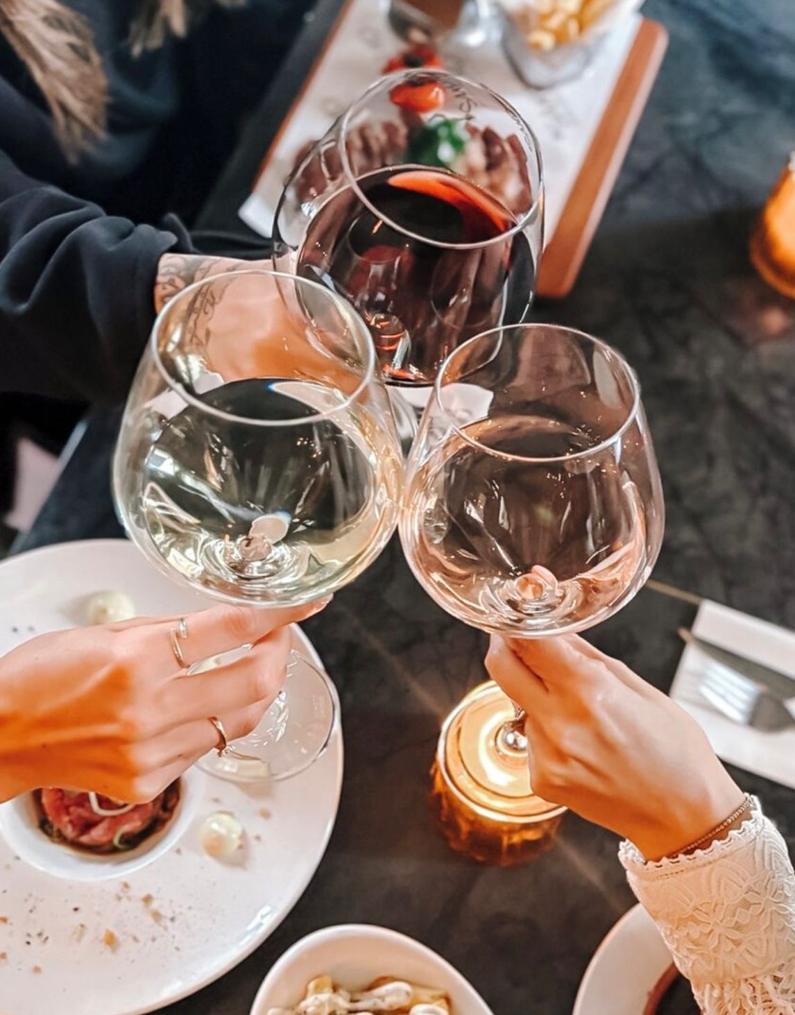 Aan een restauranttafel worden wijnglazen geheven voor een warm verlichte toast.