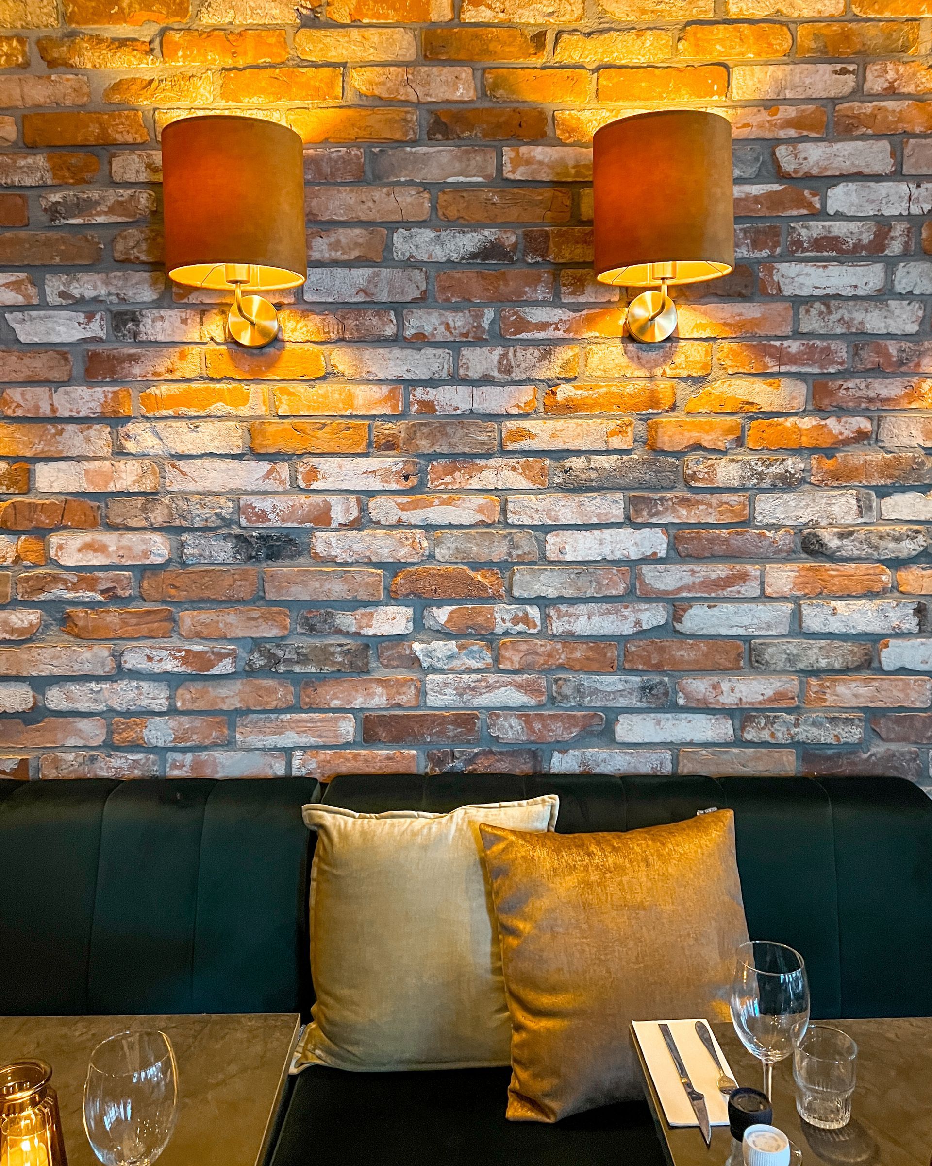 Een restaurant met een bakstenen muur en twee lampen aan de muur.