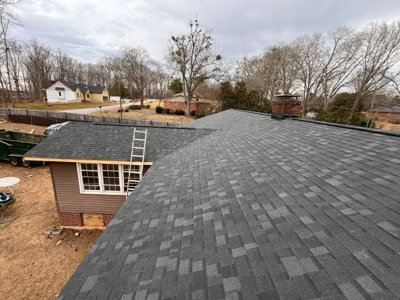 House roof with dark gray shingles under construction in a residential neighborhood