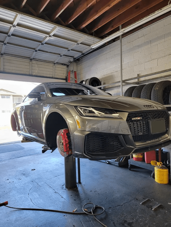 Gray sports car lifted on a jack in an auto repair garage