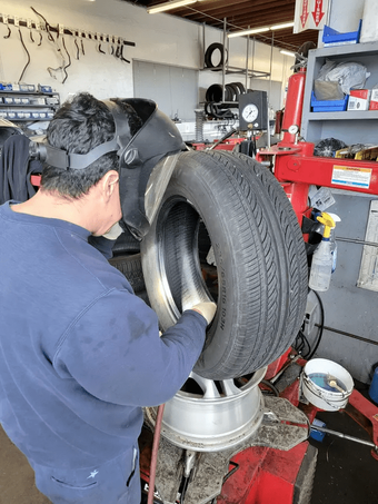 Mechanic mounting a tire on a wheel in an auto repair shop