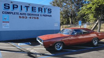 Red classic car parked outside Spiter’s auto service and repair shop on a sunny day