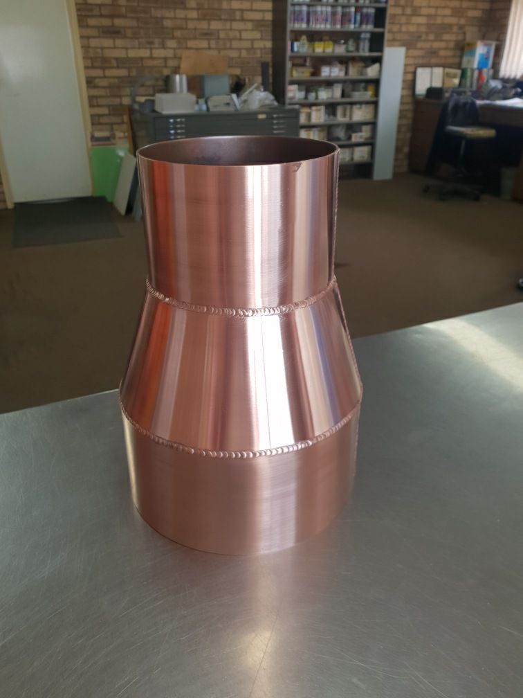 A Copper Pipe Is Sitting on Top of A Stainless Steel Table — Maitland Sheet Metal in Rutherford, NSW