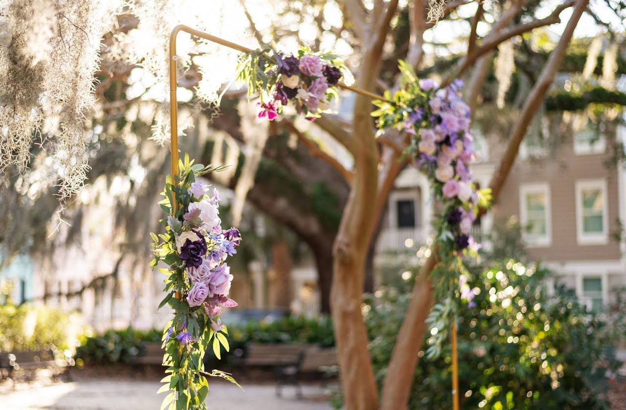 Floral arch with purple and white flowers in a sunny garden courtyard