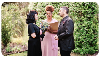 Couple exchanging vows with officiant in a garden, holding a bouquet and clipboard.