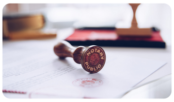 Close-up of a notary stamp resting on a document, with a blurred desk and books in the background