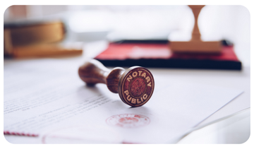 Close-up of a notary stamp resting on a document, with a blurred desk and books in the background