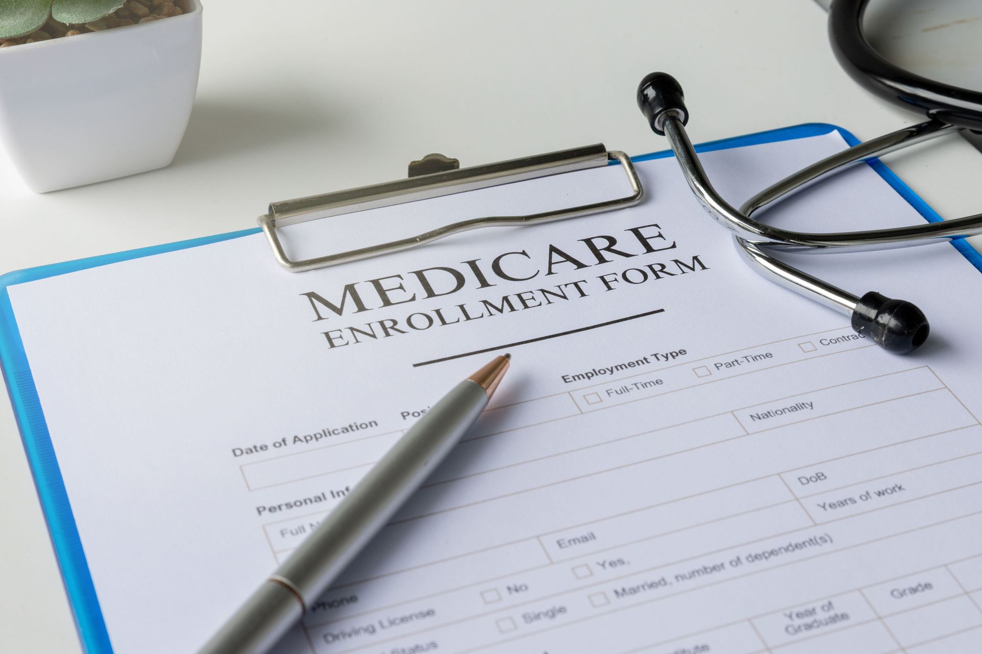 Medicare enrollment form on a clipboard with pen and stethoscope on a desk