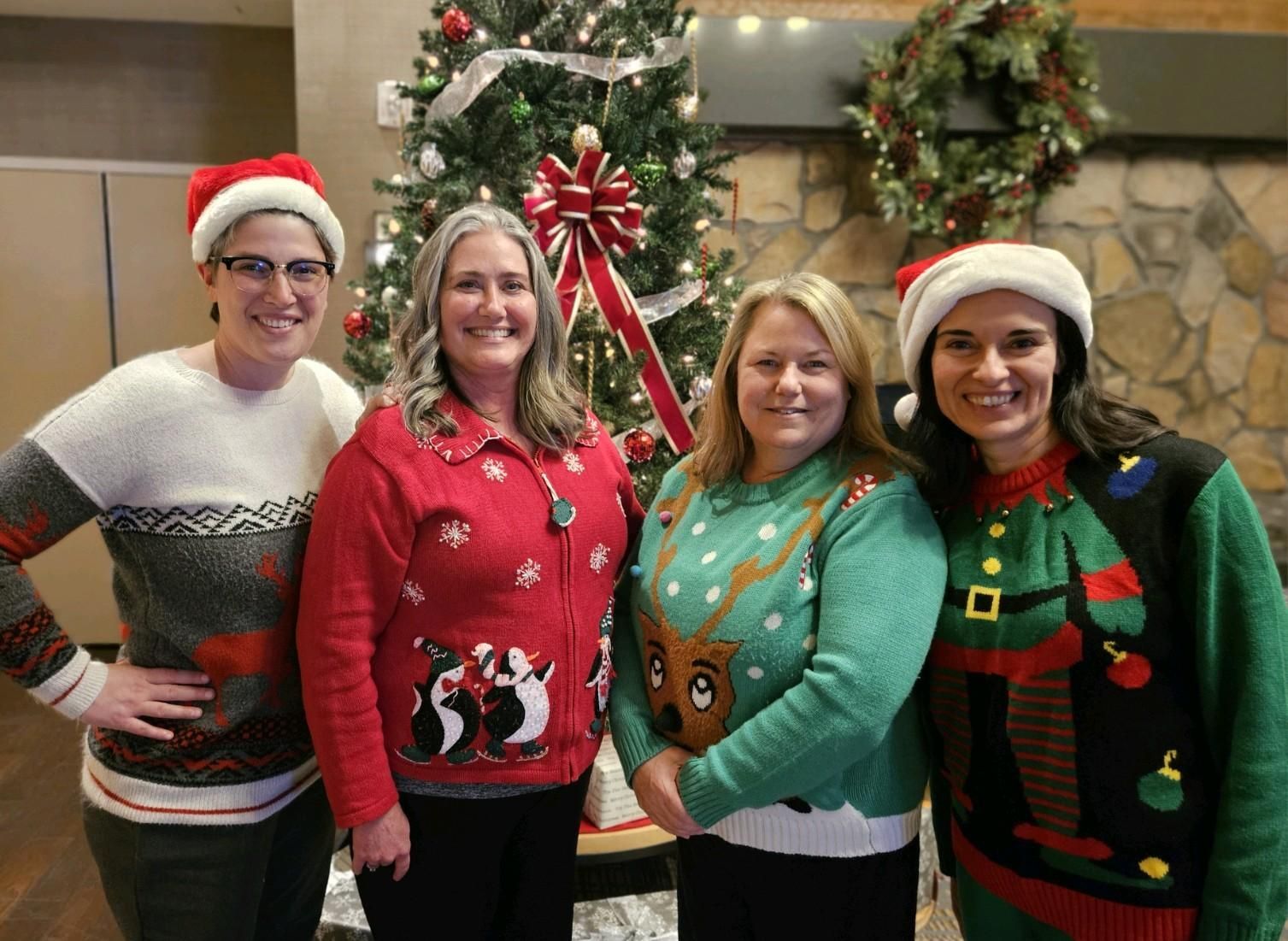 A group of women are posing for a picture in front of a christmas tree.