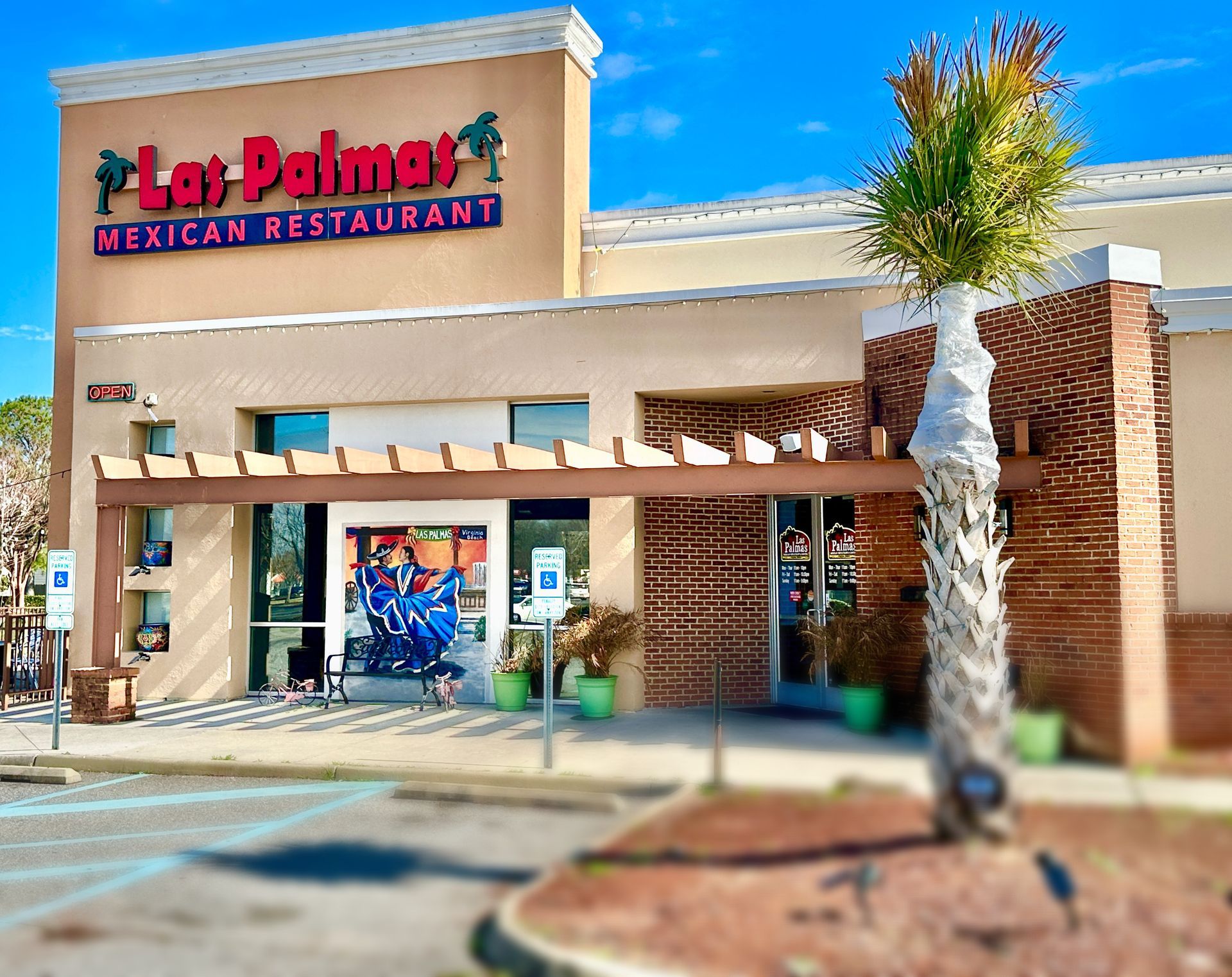 Las Palmas Mexican Restaurant exterior, beige building, palm tree, and blue sky.