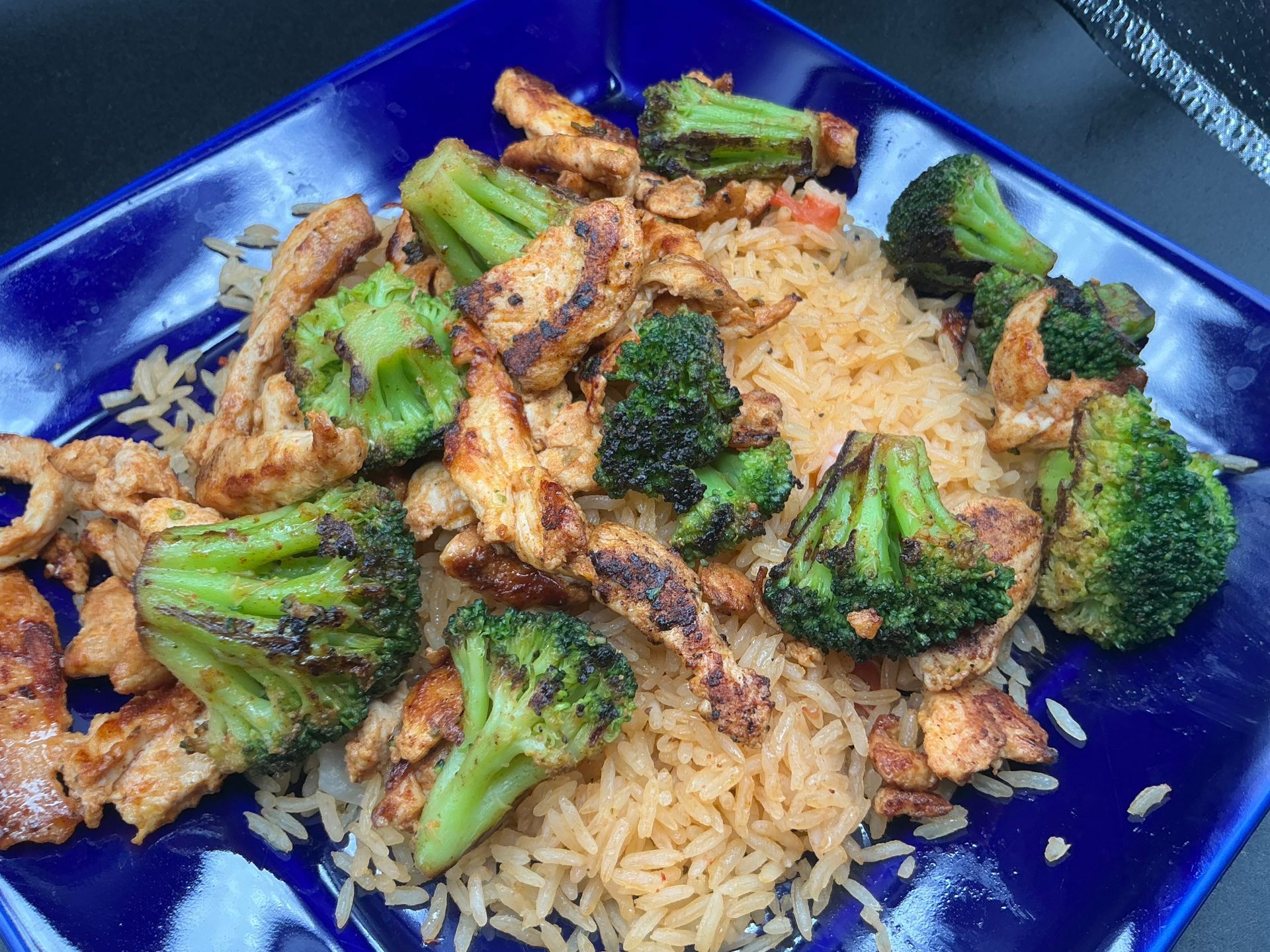 Chicken and broccoli over rice on a blue plate.
