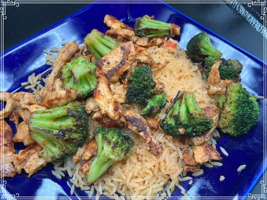 Chicken and broccoli stir-fry served over rice on a blue plate. Green broccoli, golden chicken.