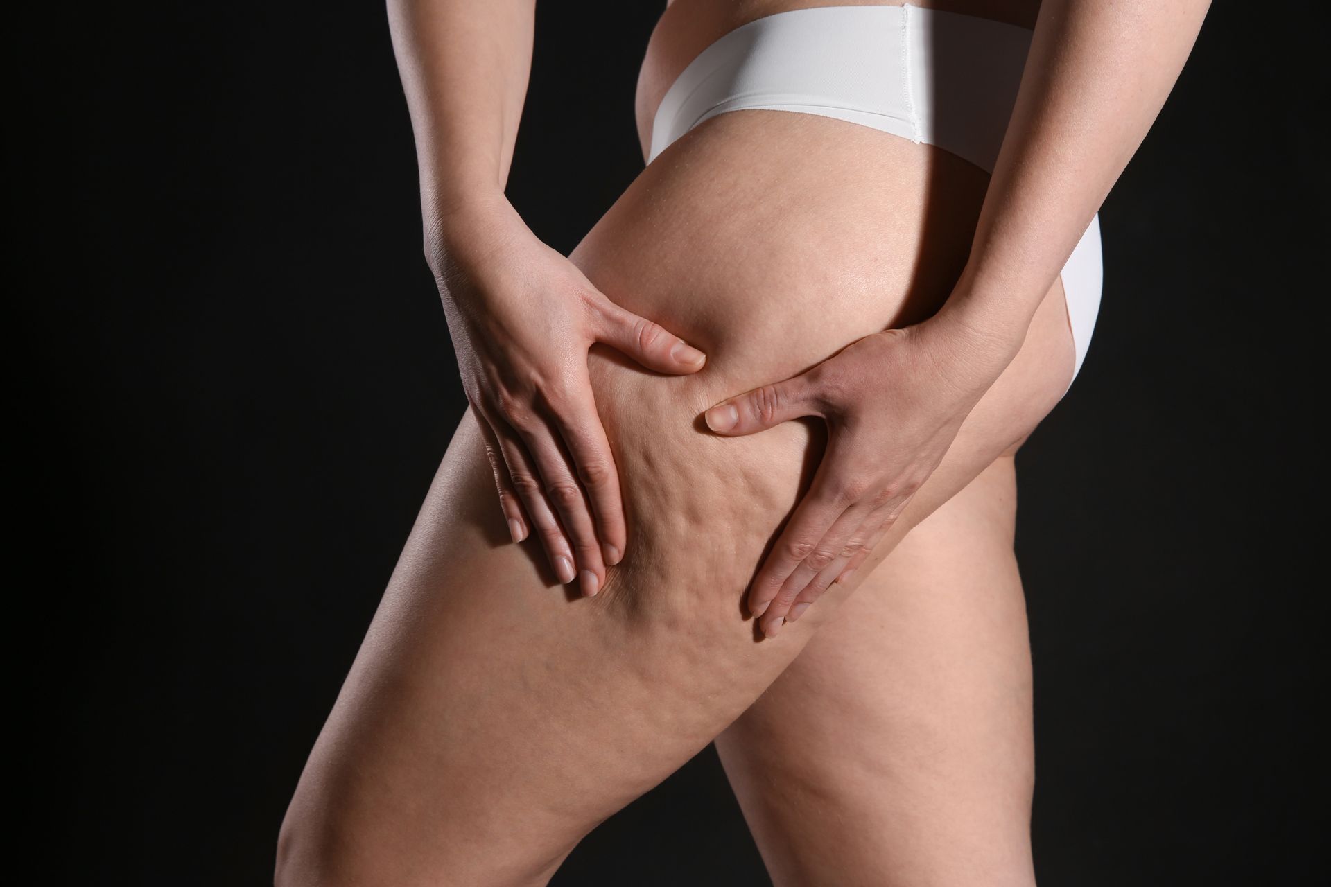 A person receives a skin treatment on their thigh with a handheld device, indoors.
