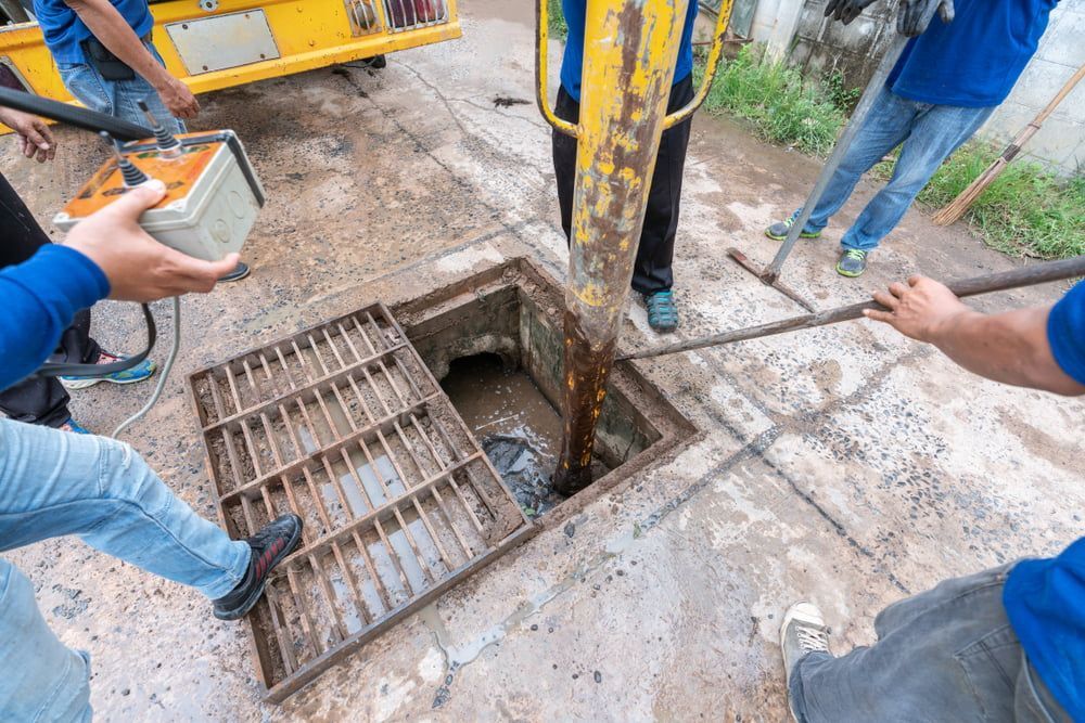 A Group Of People Are Working On A Manhole Cover — All Hours Vac Truck In Rockhampton, QLD