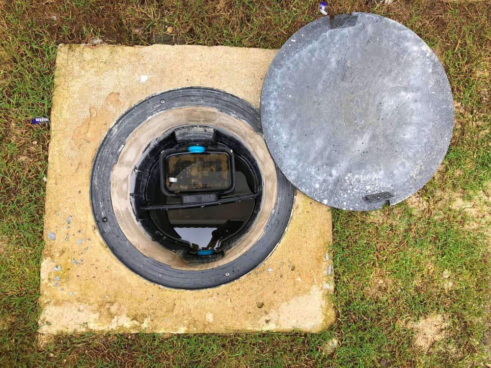 A Manhole Cover Is Sitting On Top Of A Concrete Slab In The Grass — All Hours Vac Truck In Yeppoon, QLD