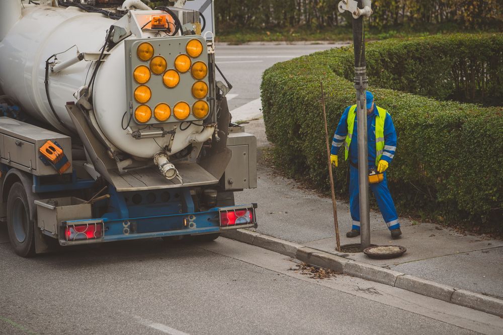 A Man Is Standing Next To A Vacuum Truck On The Side Of The Road — All Hours Vac Truck In Rockhampton, QLD