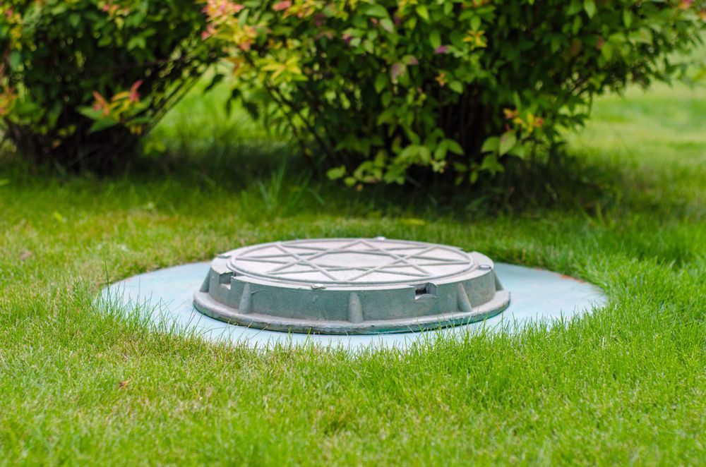 A Manhole Cover Is Sitting In The Middle Of A Lush Green Field — All Hours Vac Truck In Yeppoon, QLD