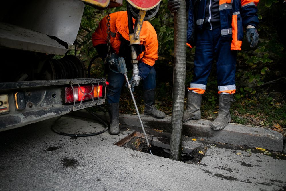 Two Men Are Working On A Manhole Cover Next To A Truck — All Hours Vac Truck In Yeppoon, QLD