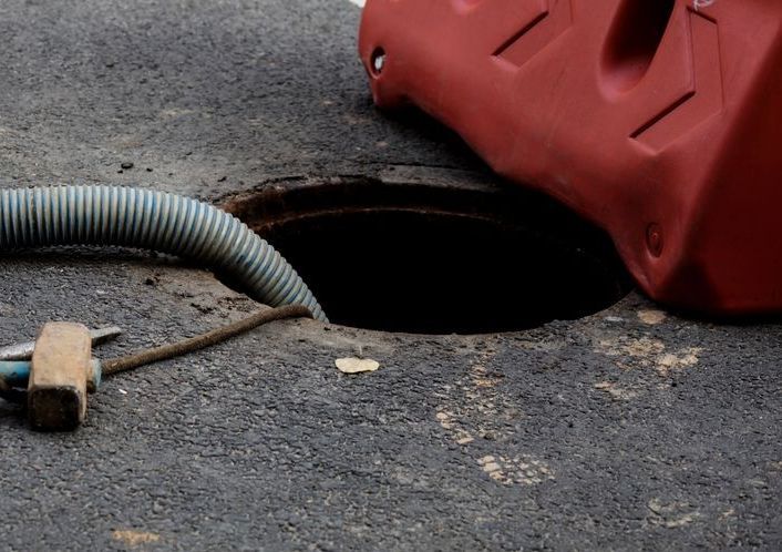 A Manhole With A Hose Attached To It Is Being Filled With Water — All Hours Vac Truck In Lakes Creek, QLD
