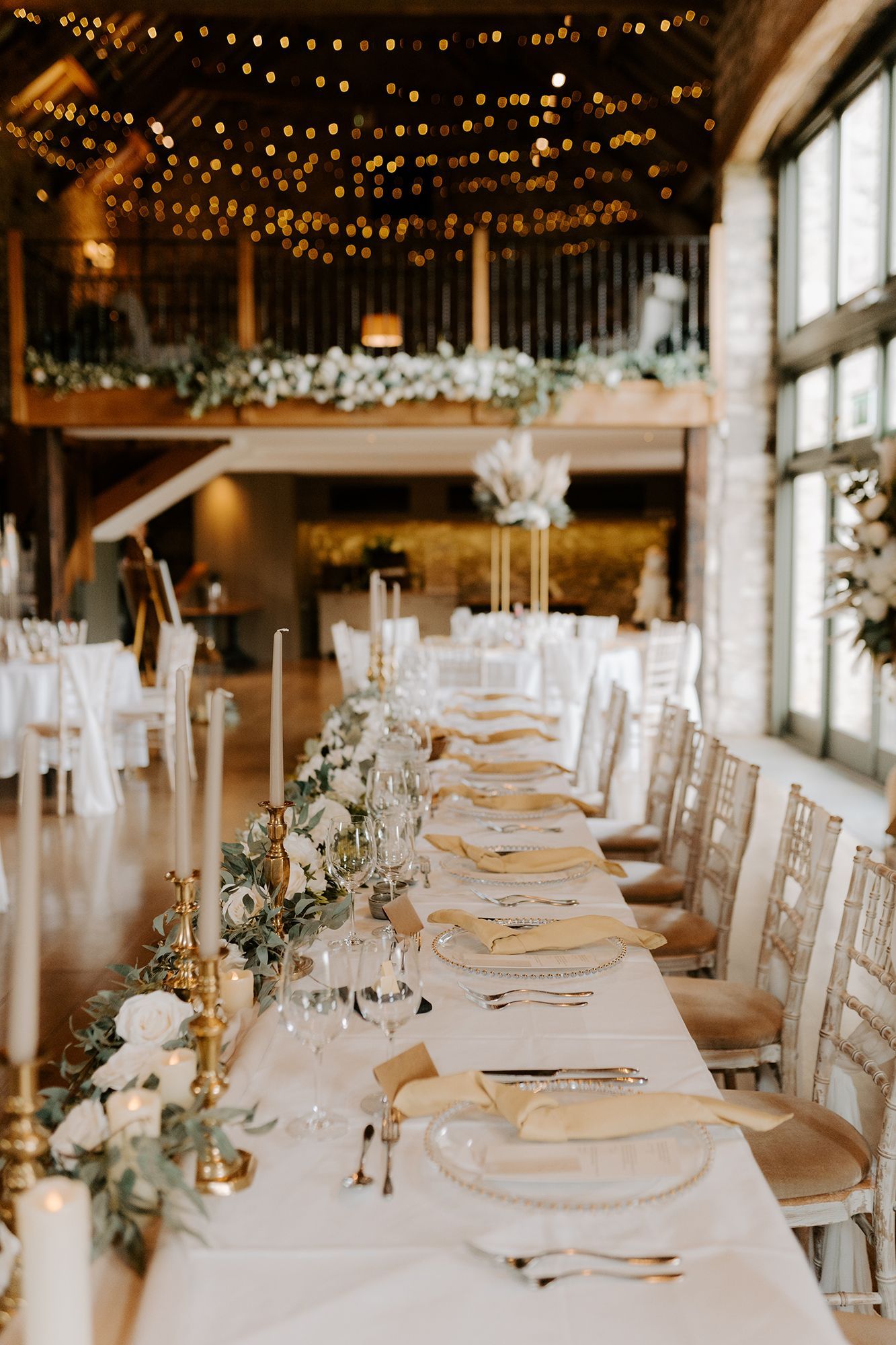 A long table with plates , candles , and flowers on it in a room.