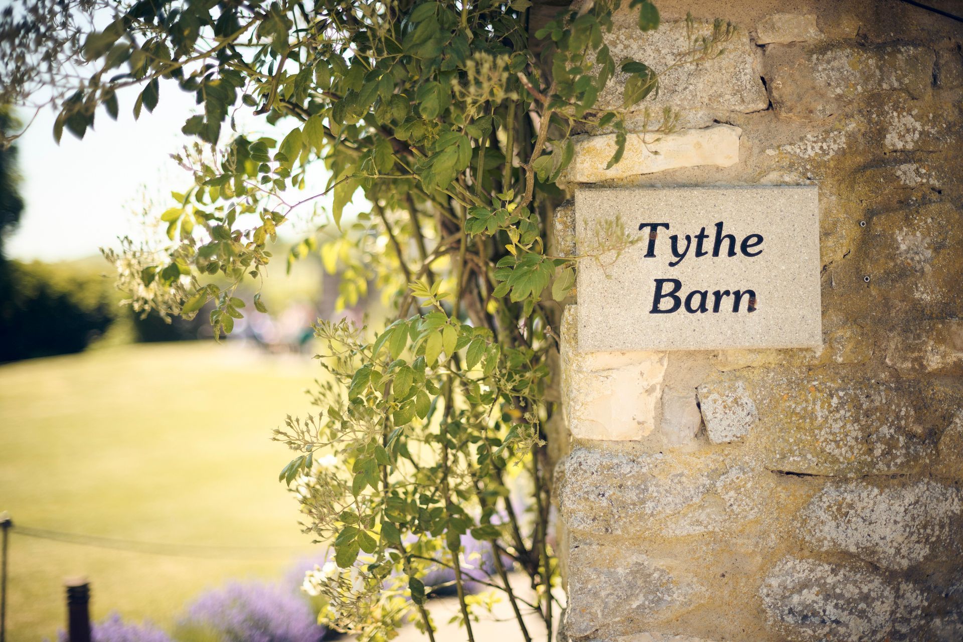 A stone wall with a sign that says tythe barn on it.