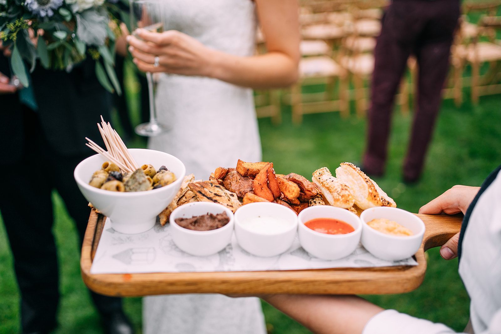 A bride and groom are holding a tray of food.