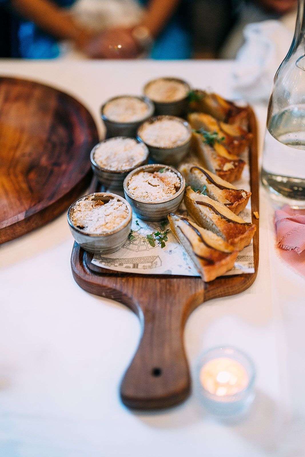 A wooden cutting board with a variety of food on it on a table.