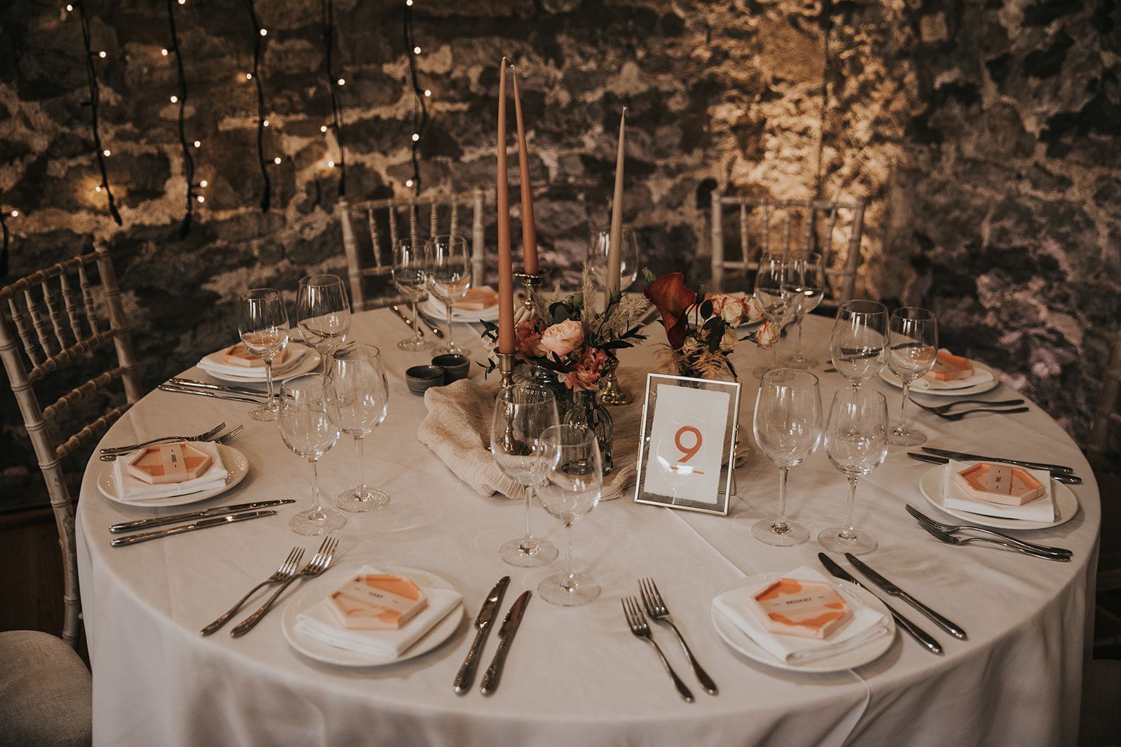A table set for a wedding reception with plates , utensils , and candles.