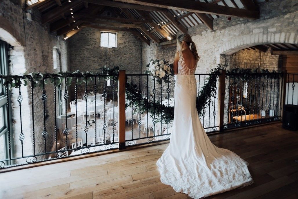 bride standing on balcony in tythe barn at priston mill, bath