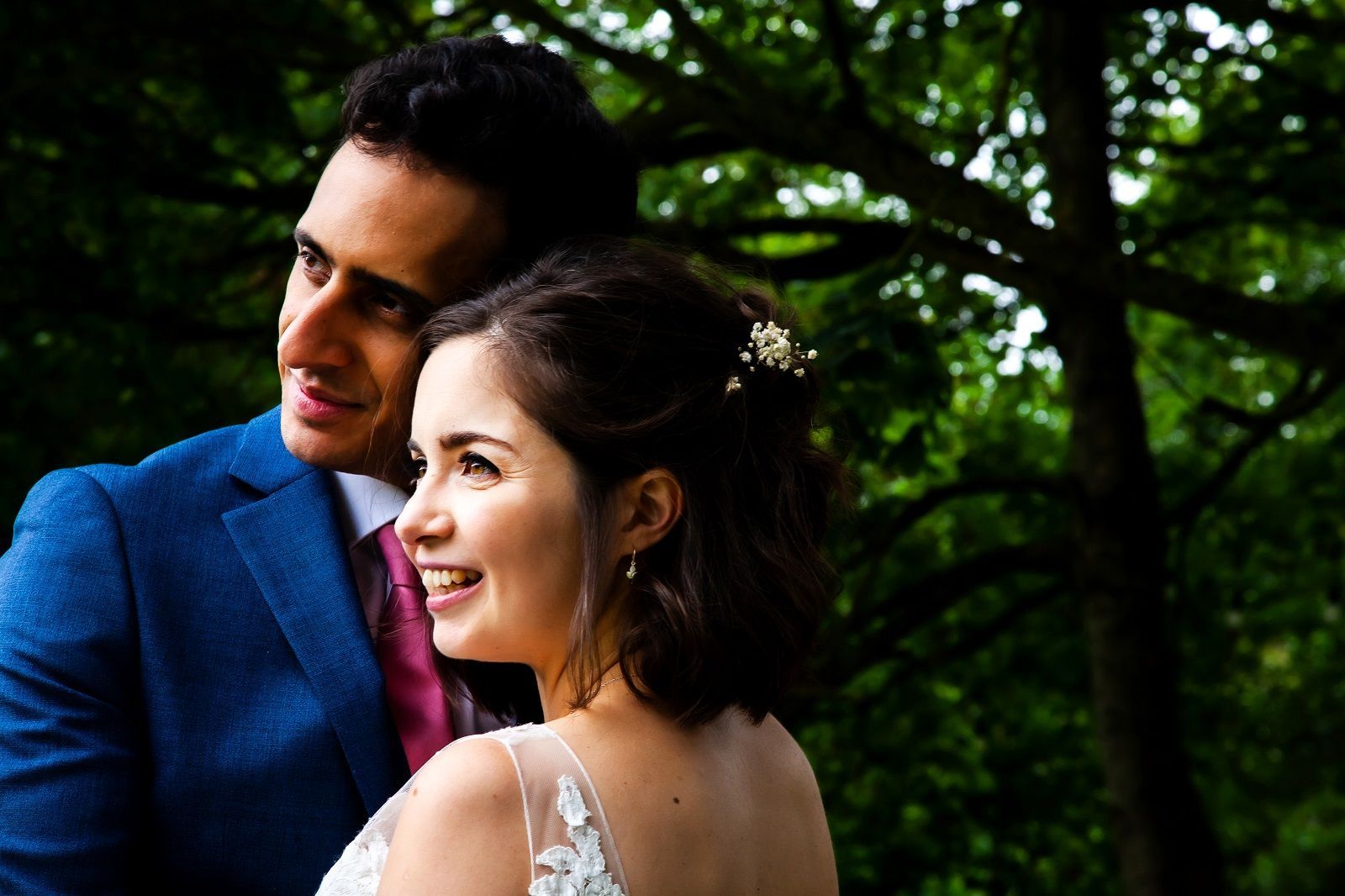 A bride and groom are posing for a picture in the woods.