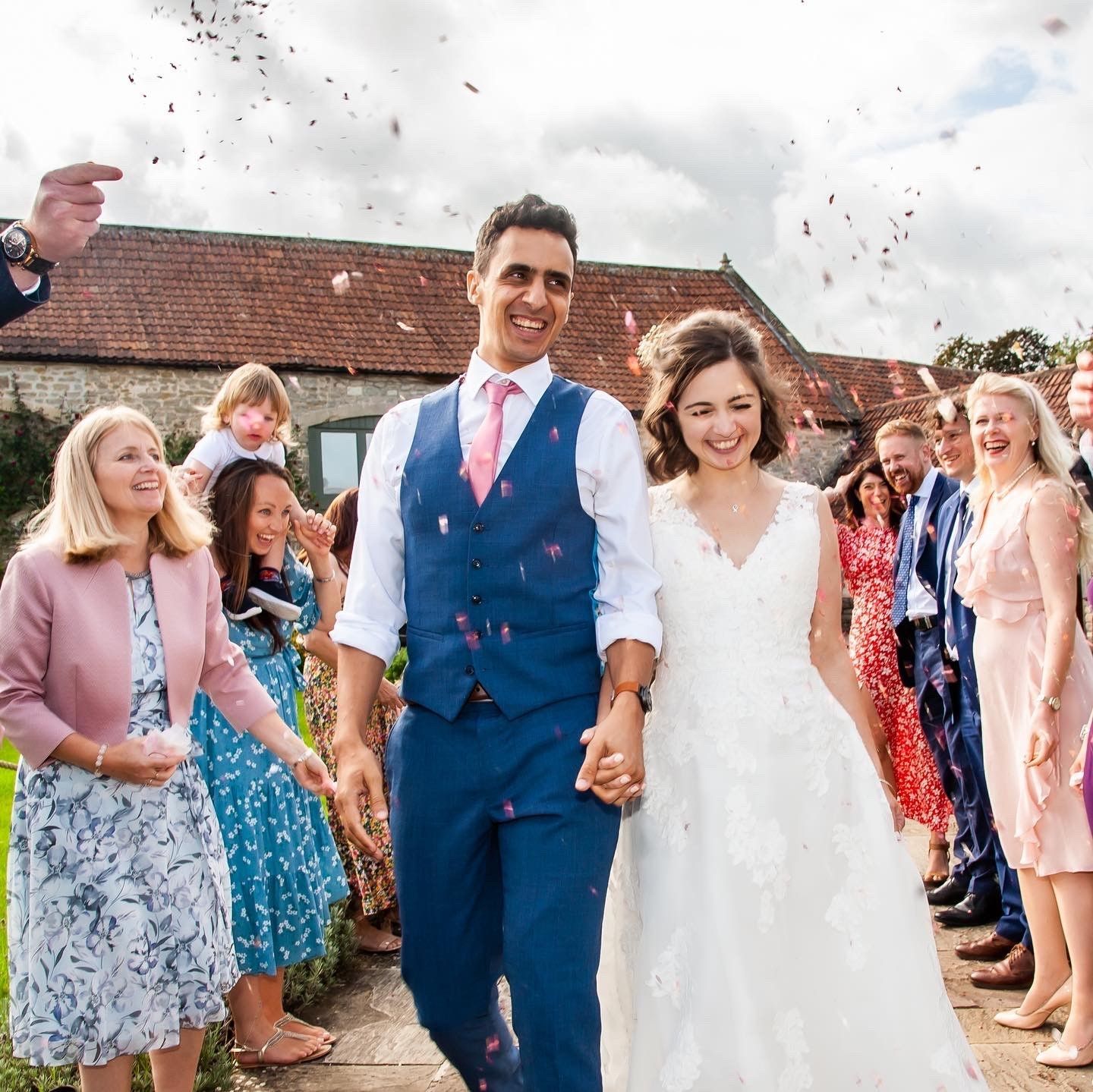 A bride and groom are walking through a crowd of people at their wedding