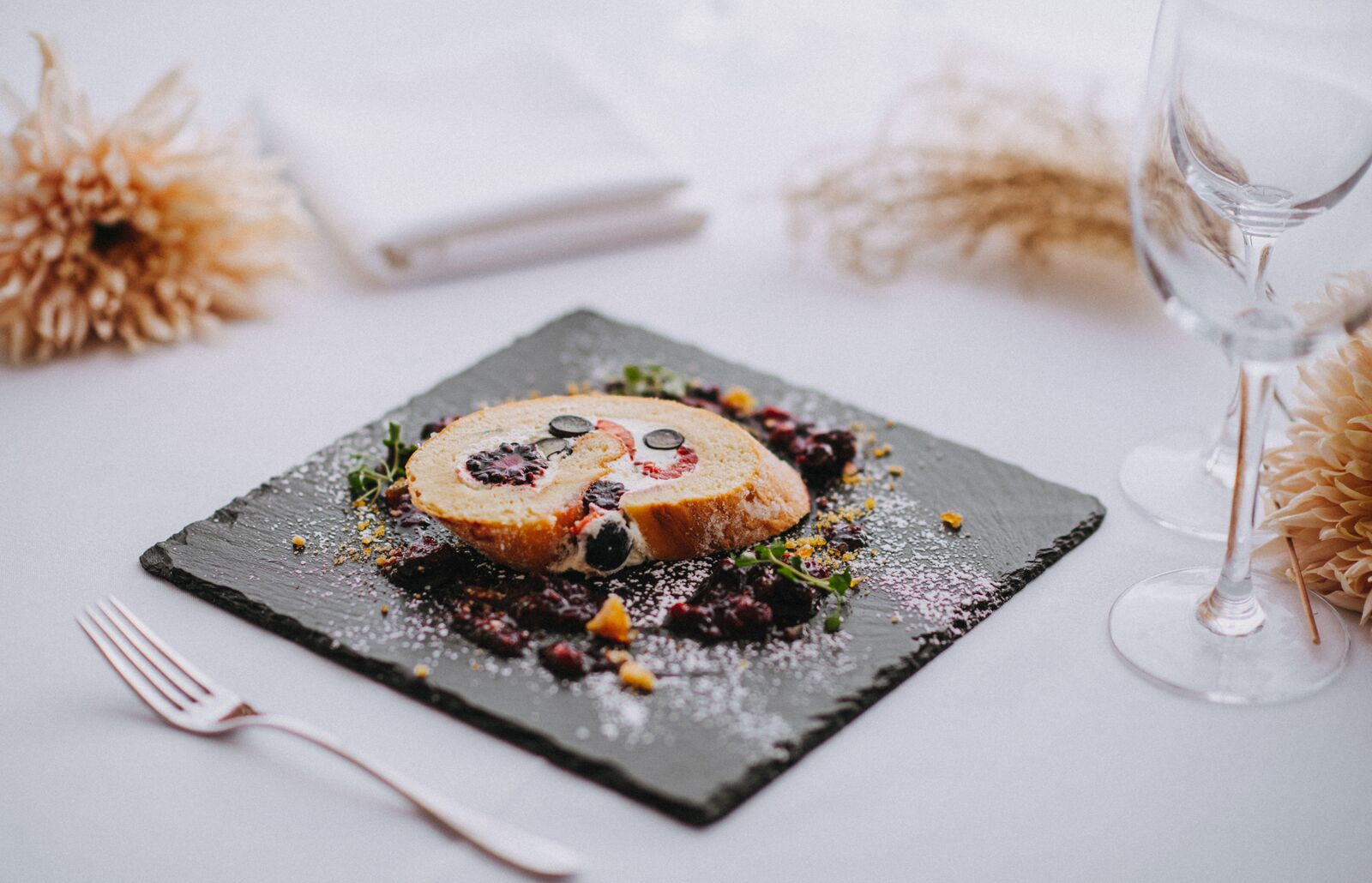 A plate of food with a fork and a glass of wine on a table.