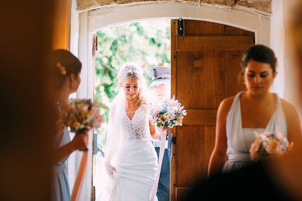A bride and her bridesmaids are walking out of a church.