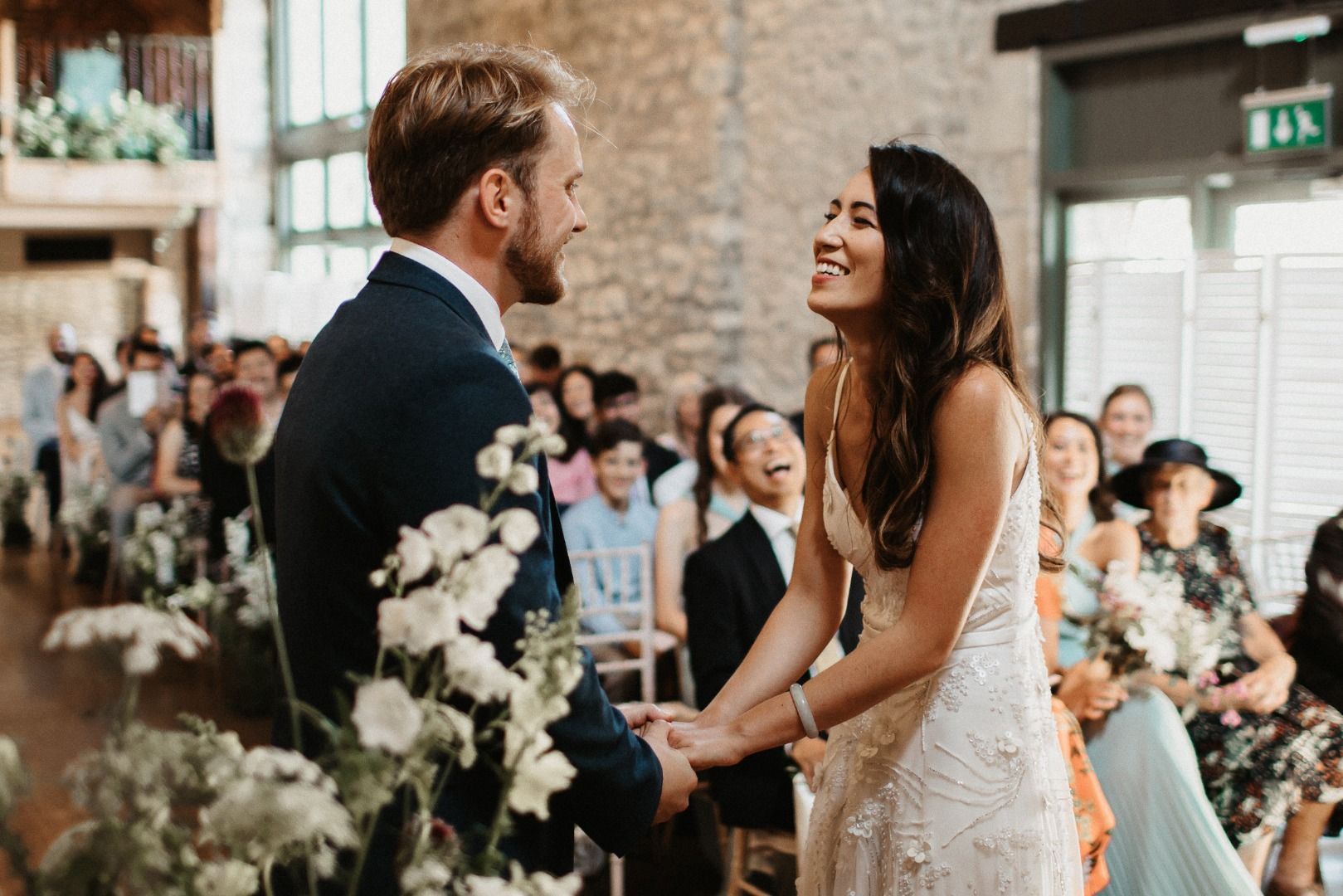 A bride and groom are holding hands during their wedding ceremony.