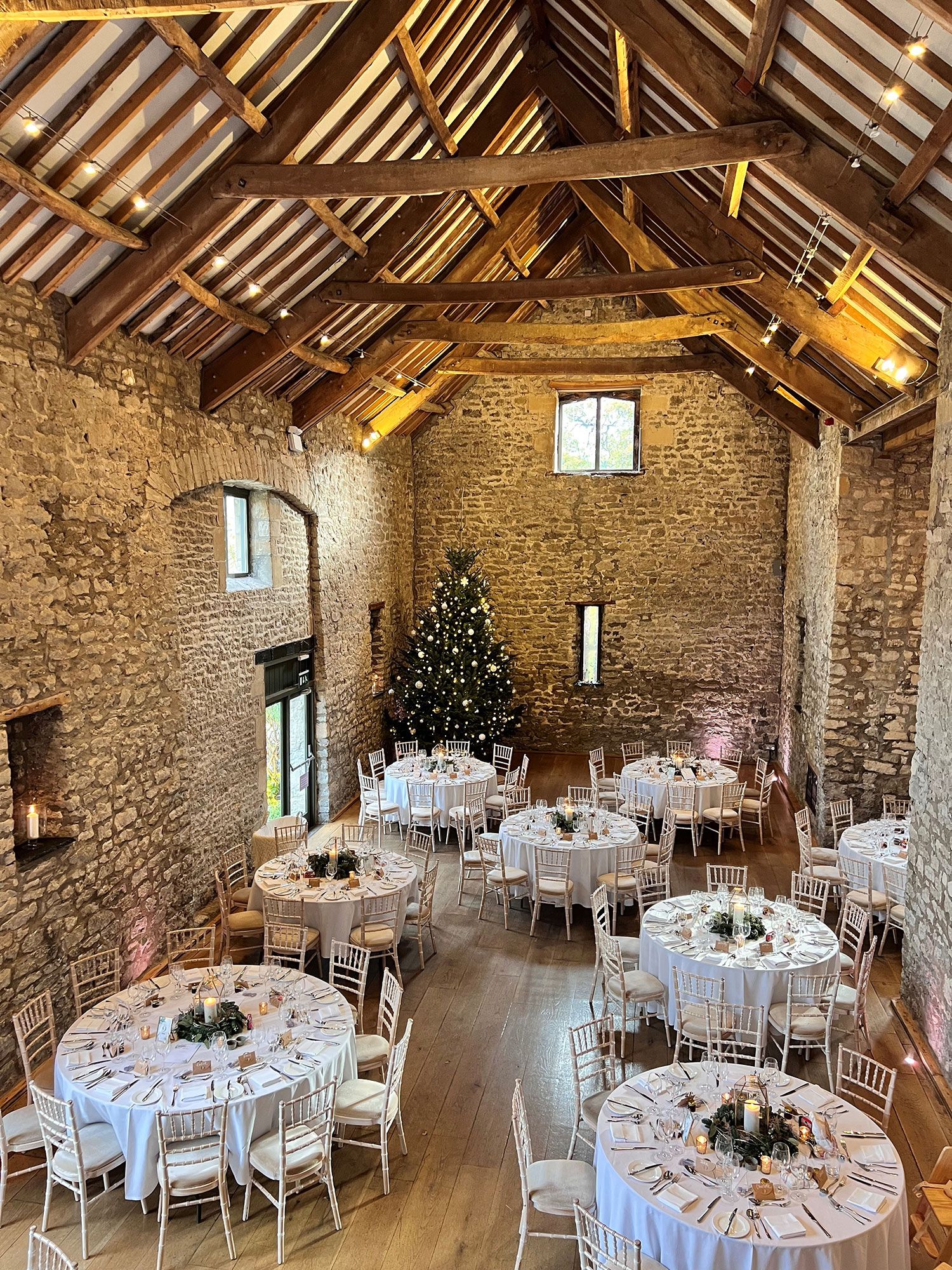 A large room filled with tables and chairs and a christmas tree.