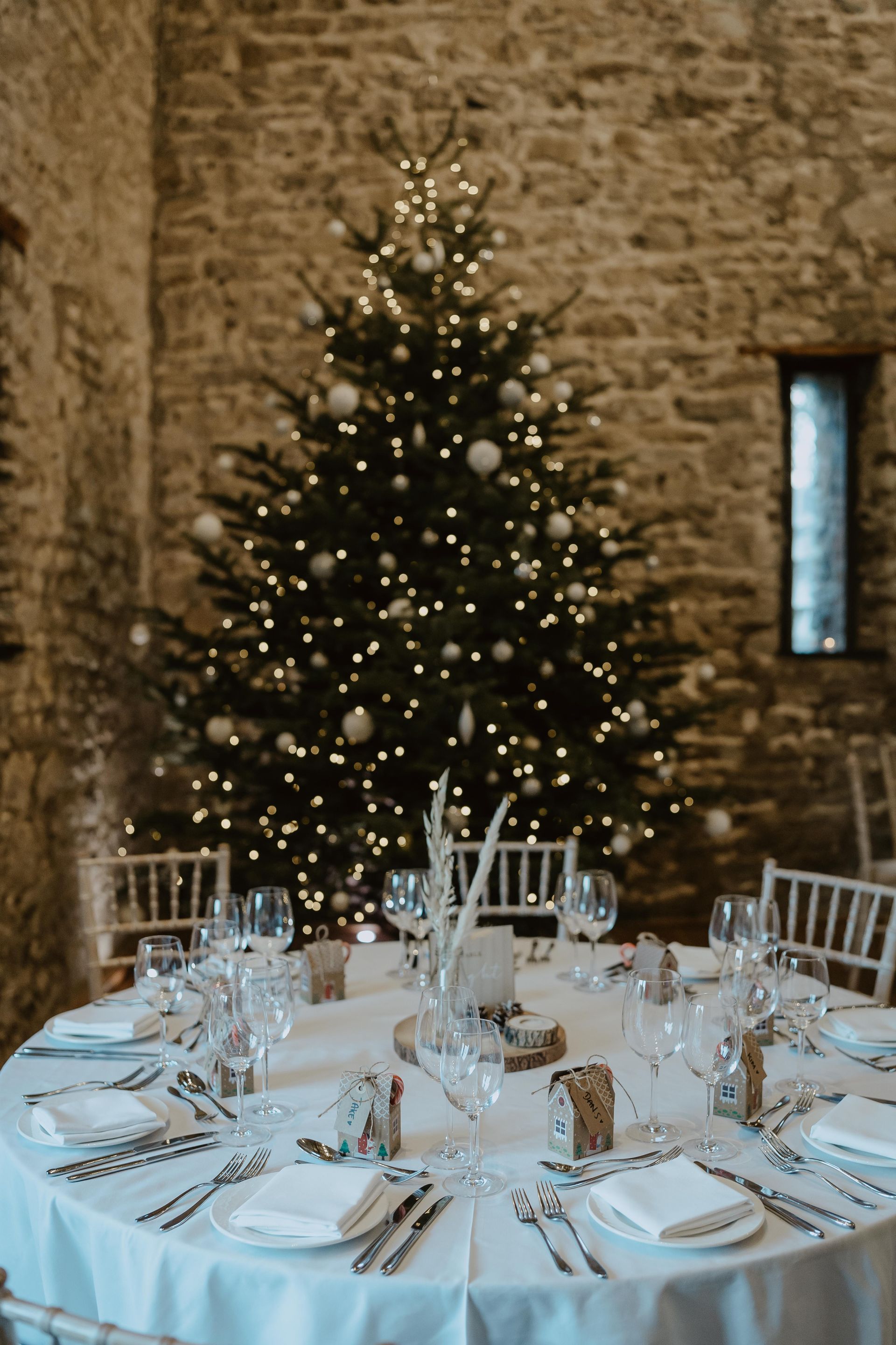 A table set for a wedding reception with a christmas tree in the background.