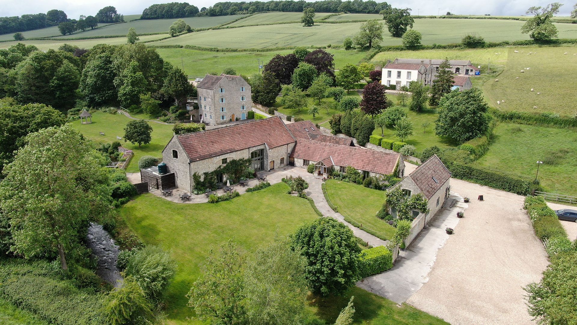 An aerial view of a large house in the middle of a lush green field