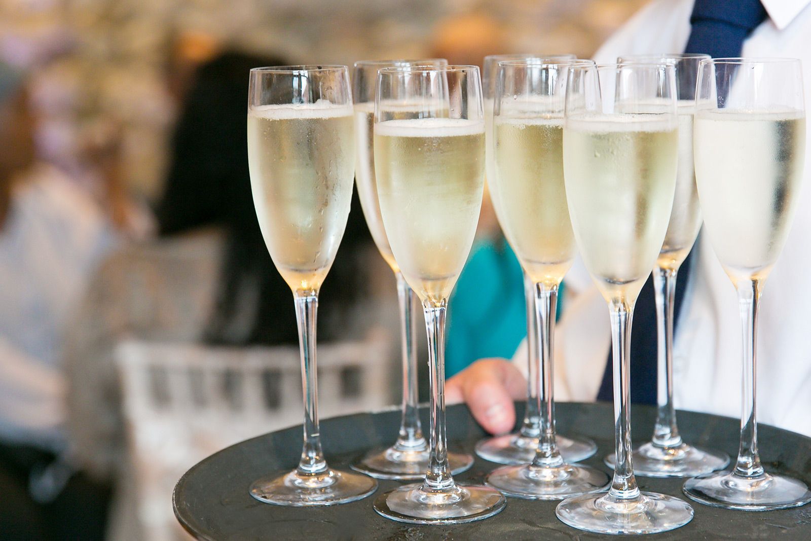 A waiter is holding a tray of champagne glasses filled with champagne.