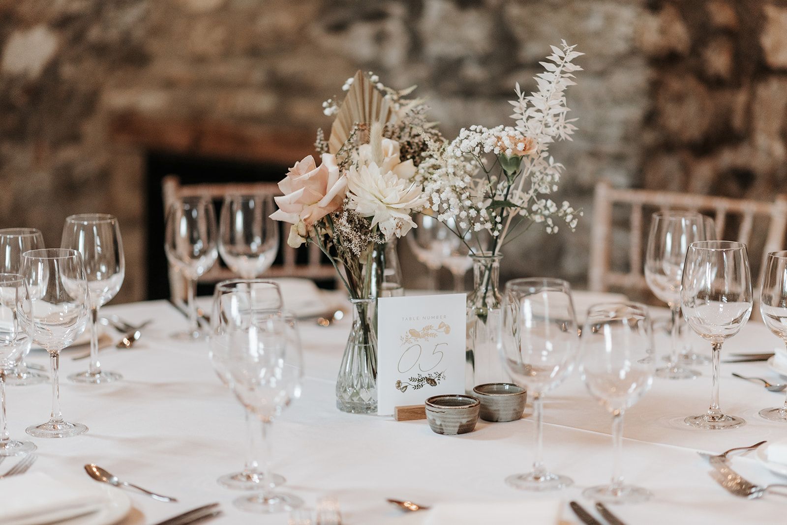 A table set for a wedding reception with a vase of flowers on it.