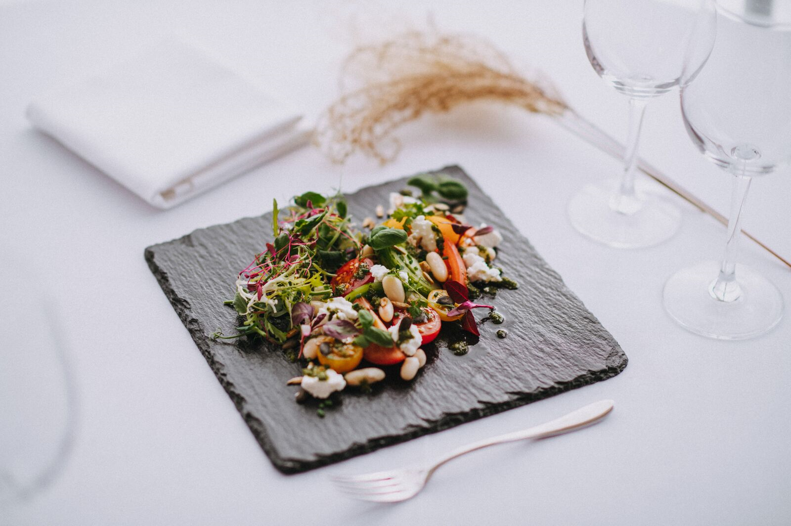 A plate of food is sitting on a table next to wine glasses.