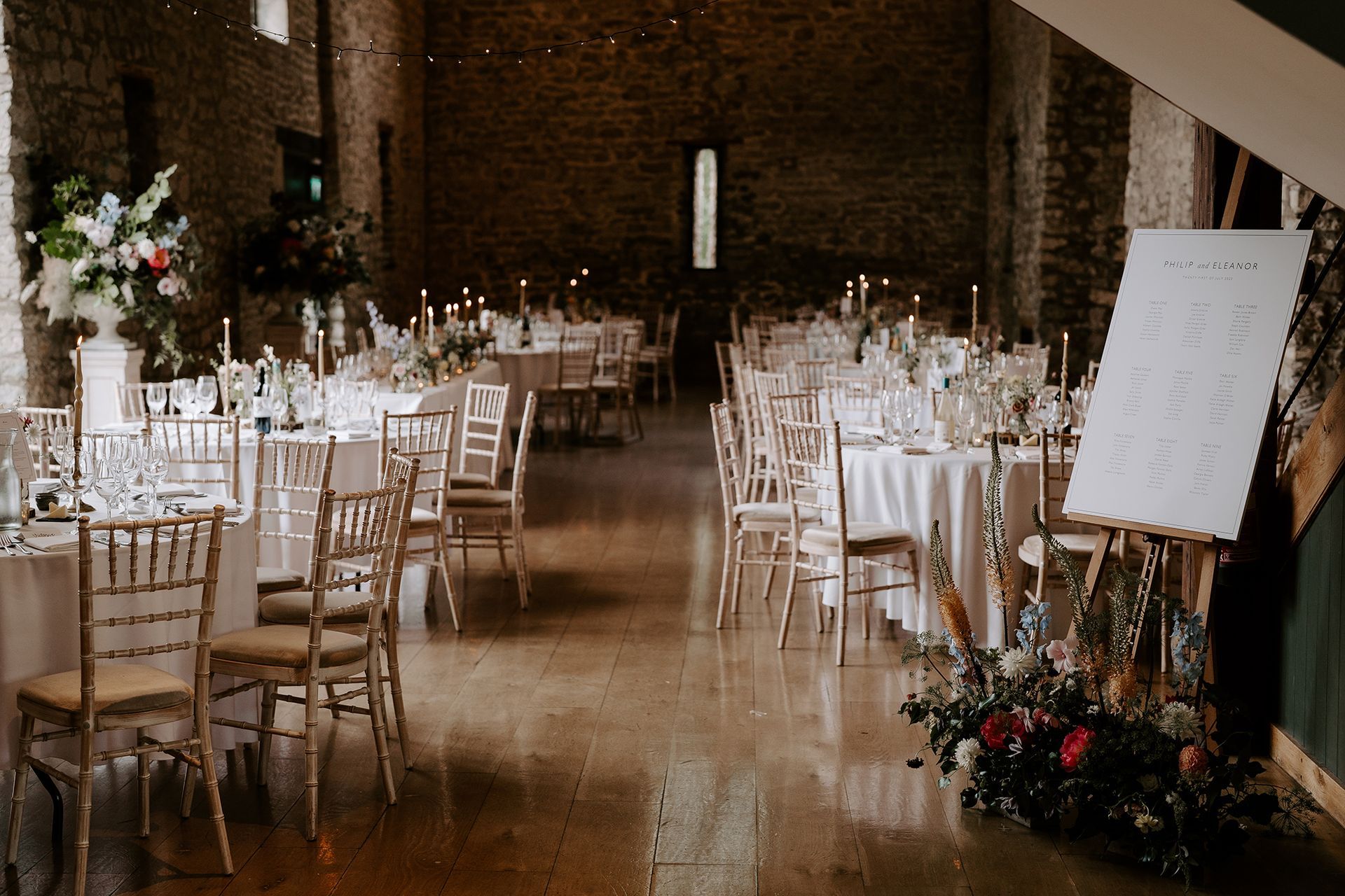 A large room with tables and chairs set up for a wedding reception.