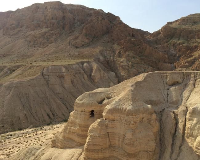 Sandy cliffs and hills, desert landscape with a cave entrance.