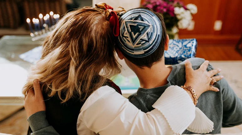 a woman hugs a man wearing a kippah