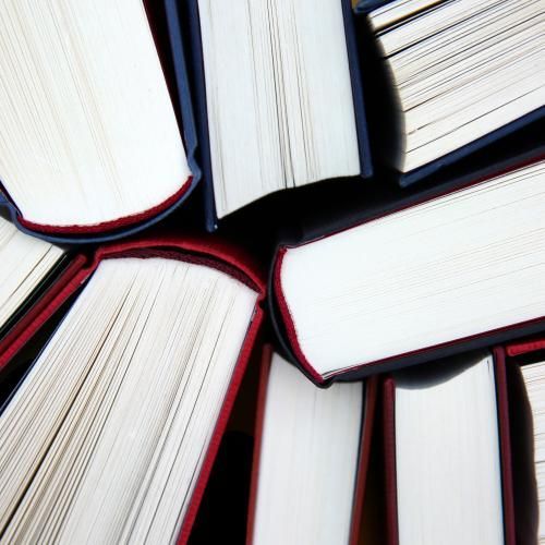 Books stacked together, showing white pages and colored spines.