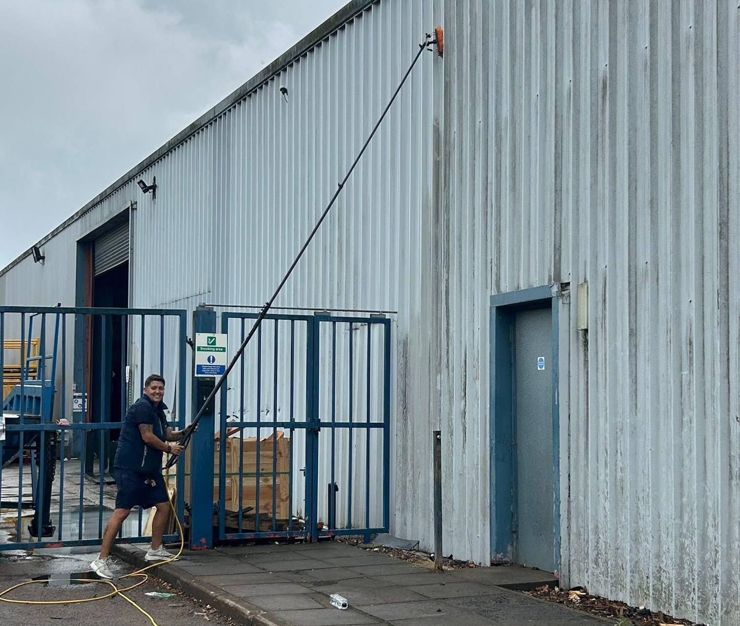 Zoe from Ellie's Windows cleaning the side of a dirty grey commercial property