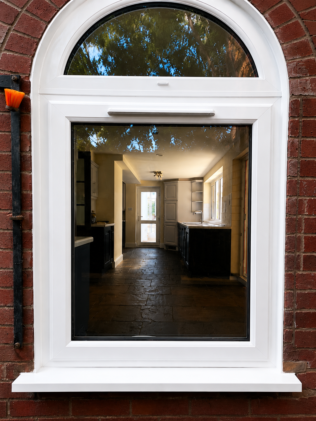 White arched window on a brick wall, showing a dim hallway inside a building