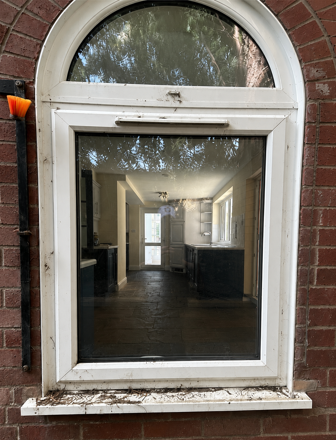 White-framed arched window in a brick wall, showing a dim interior hallway beyond.