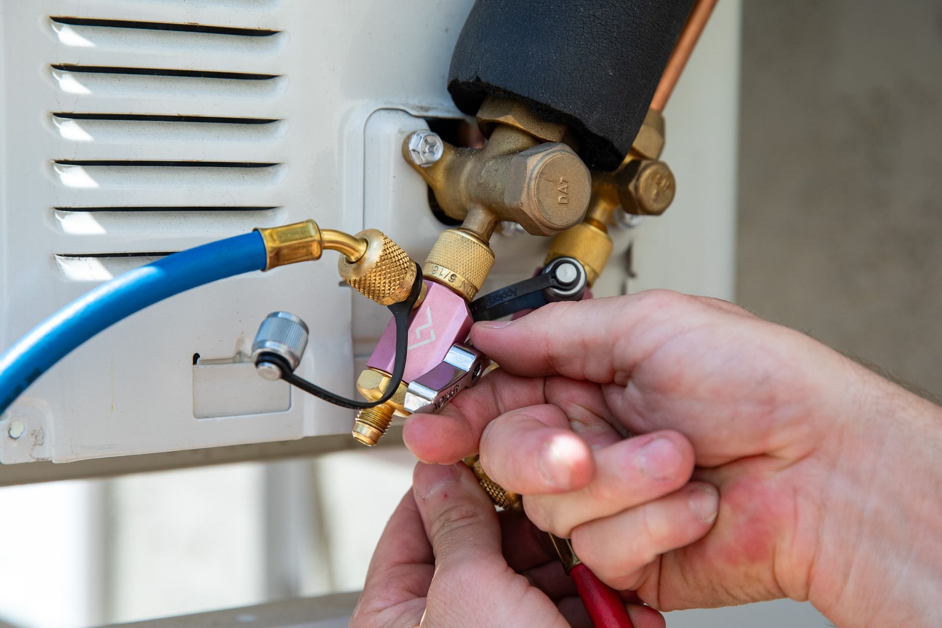 Williams Mechanical Co technician connecting manifold gauges to an AC service valve